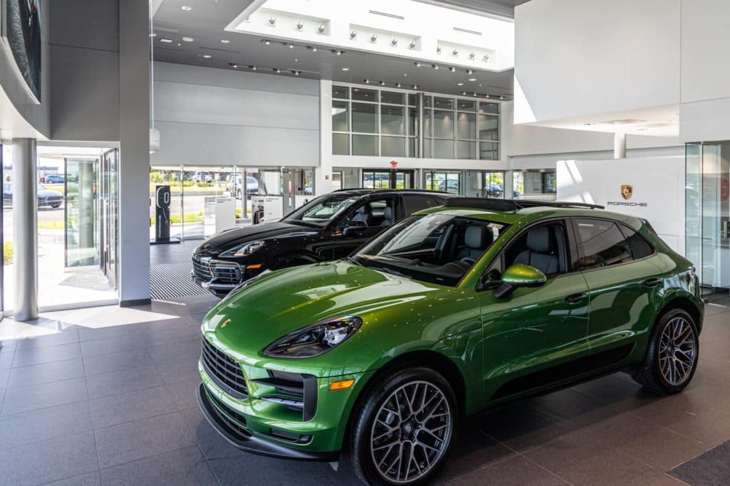 inside the dealership with a green porsche suv infront of the glass walls