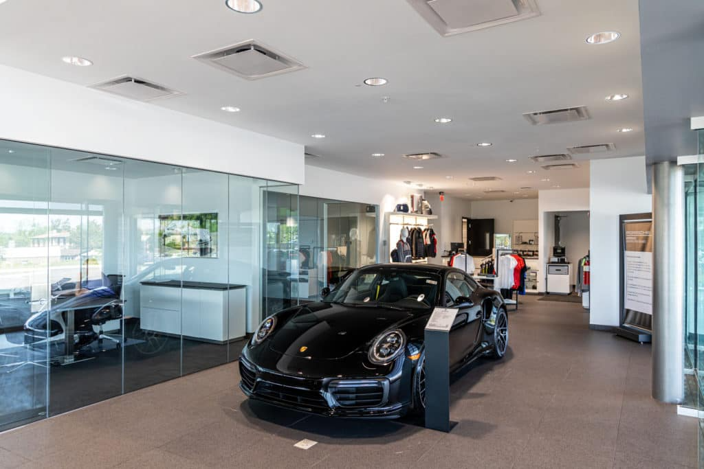Inside the dealership with a black porsche in the center of the hallway