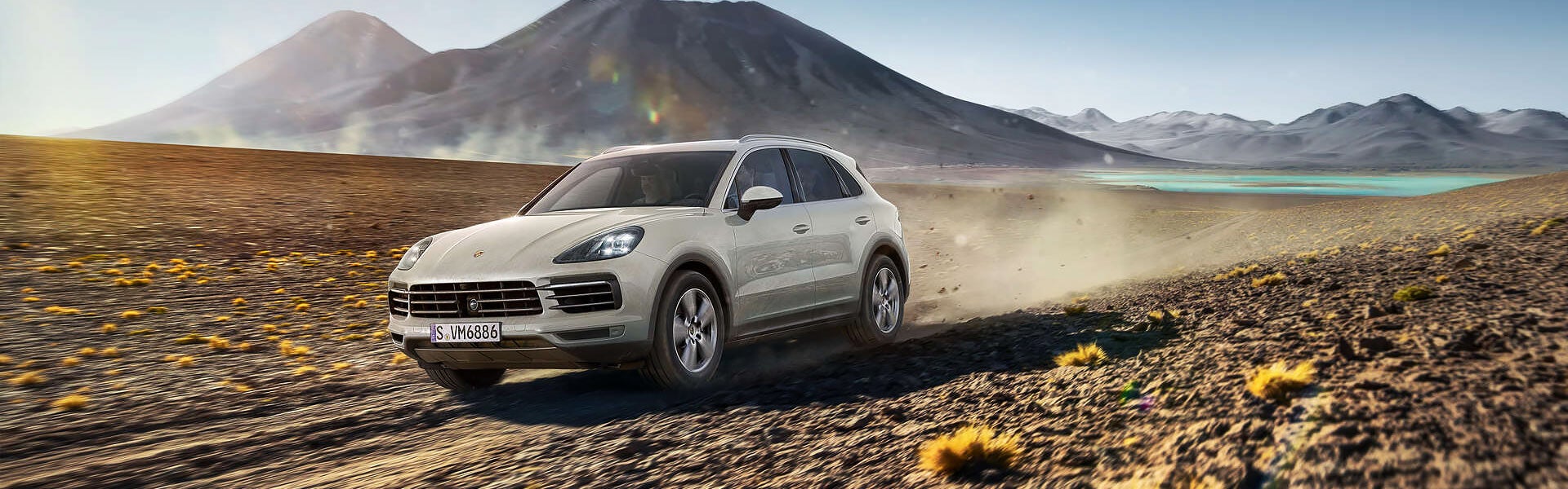 Porsche Cayenne driving on a road in dessert with mountains in the background